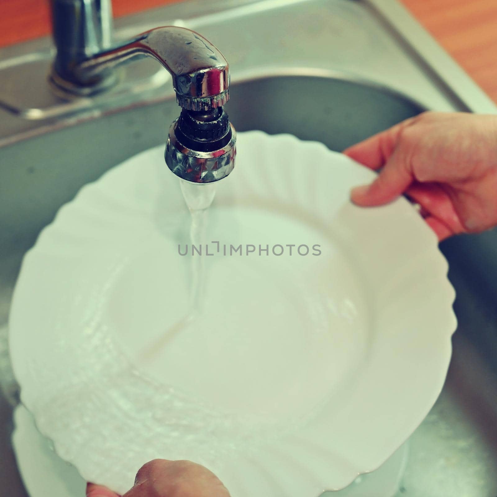 Hand washing dishes. Hand with sponge and sink in kitchen washing dirty dishes - plate. by Montypeter