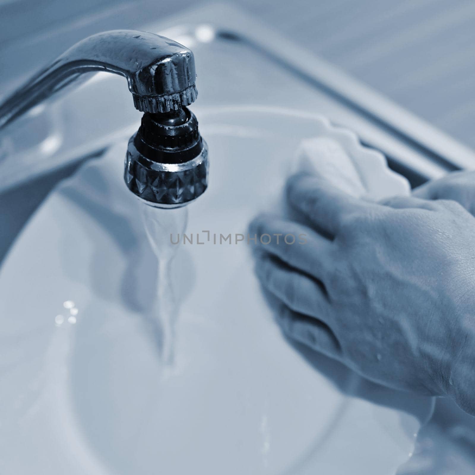 Hand washing dishes. Hand with sponge and sink in kitchen washing dirty dishes - plate. by Montypeter