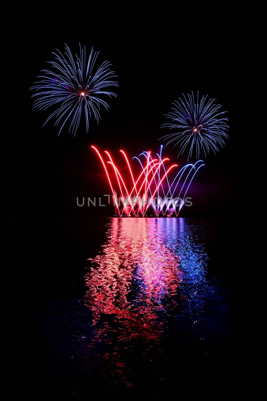 Beautiful colorful fireworks on the water surface. Night scene. Concept for holidays and celebrations.