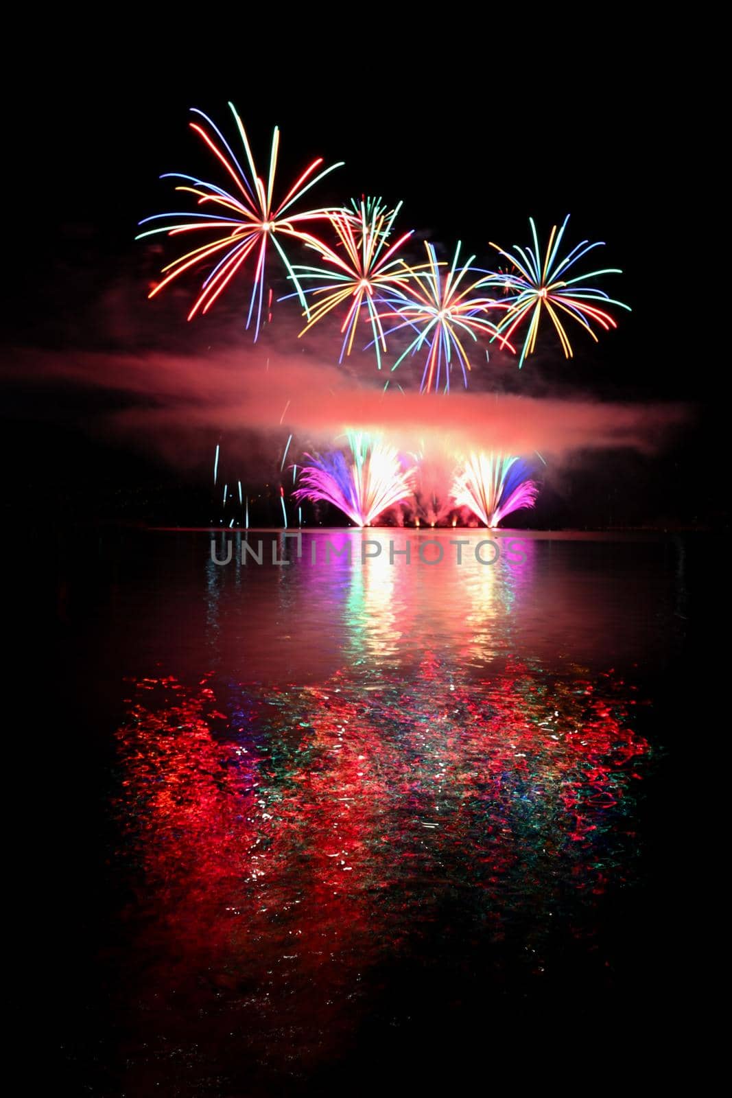 Beautiful colorful fireworks on the water surface. Night scene. Concept for holidays and celebrations.