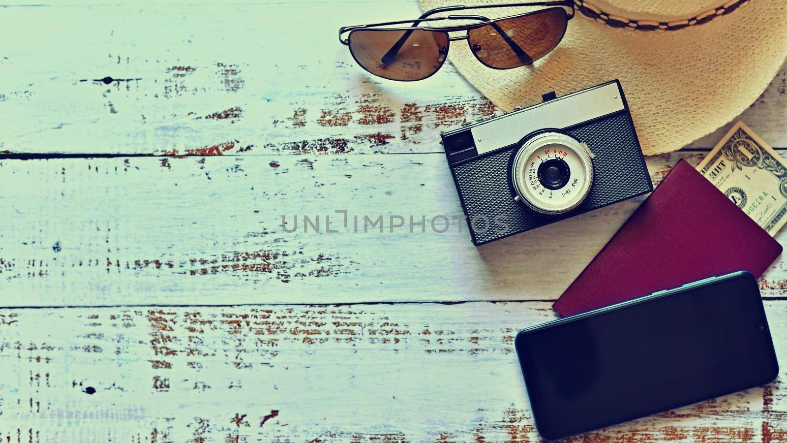 Items for summer vacation: a camera, passport,smartphone, money, hat, sunglasses. Wooden background, top view with Copy space. Beautiful summer concept for travel and summer vacation.