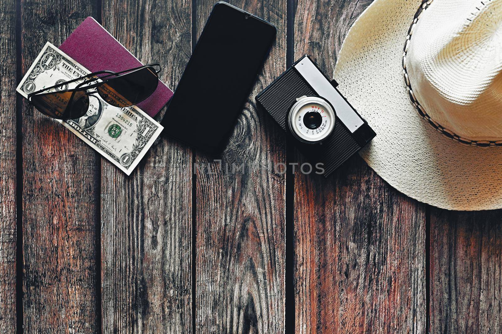 Items for summer vacation: a camera, passport,smartphone, money, hat, sunglasses. Wooden background, top view with Copy space. Beautiful summer concept for travel and summer vacation.