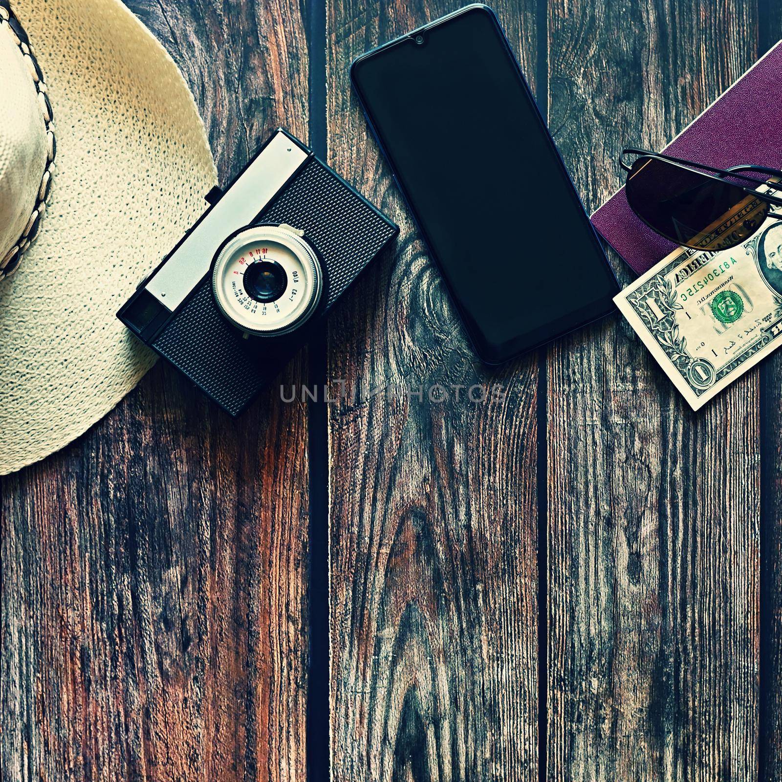 Items for summer vacation: a camera, passport,smartphone, money, hat, sunglasses. Wooden background, top view with Copy space. Beautiful summer concept for travel and summer vacation. by Montypeter