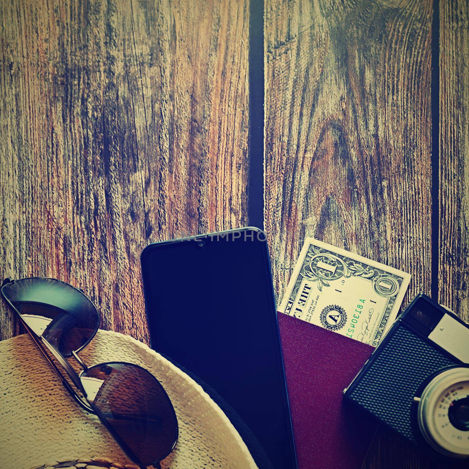 Items for summer vacation: a camera, passport,smartphone, money, hat, sunglasses. Wooden background, top view with Copy space. Beautiful summer concept for travel and summer vacation. by Montypeter