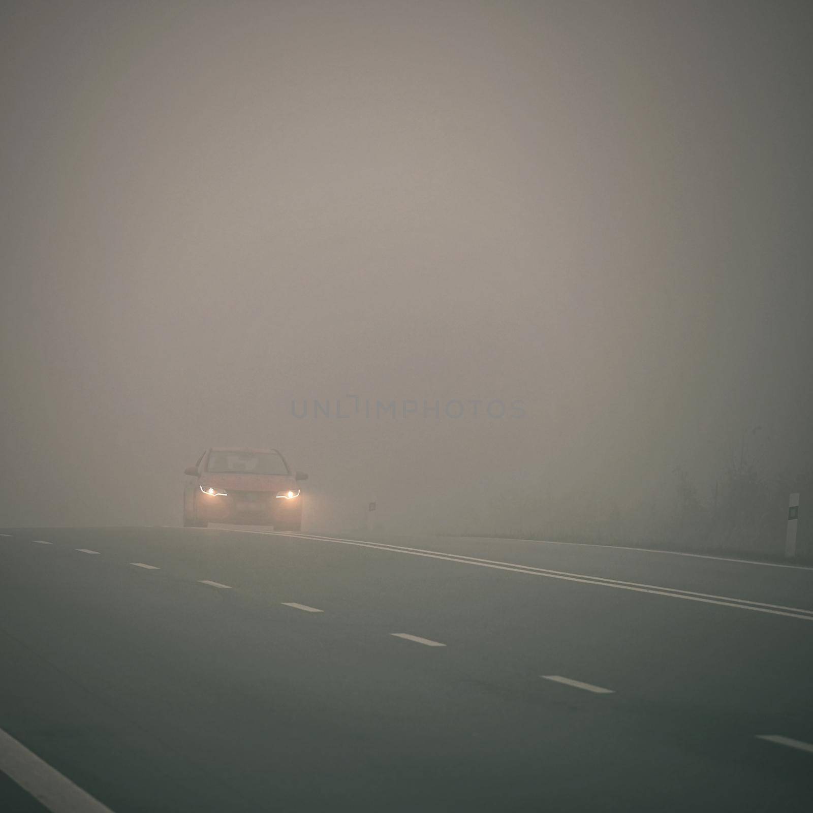 Bad weather driving - foggy hazy country road. Motorway - road traffic. Winter time.