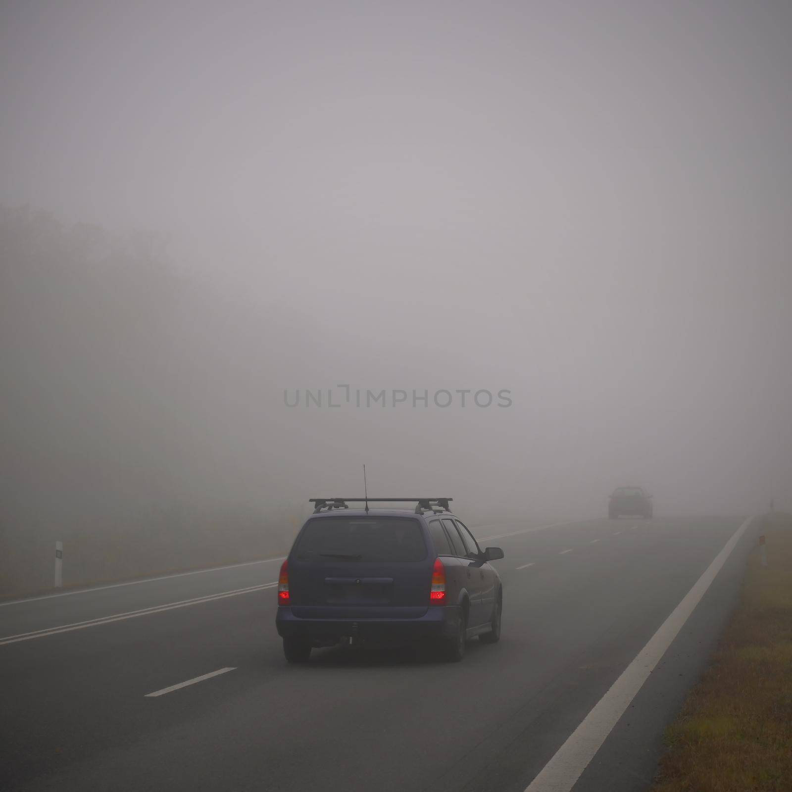 Bad weather driving - foggy hazy country road. Motorway - road traffic. Winter time.