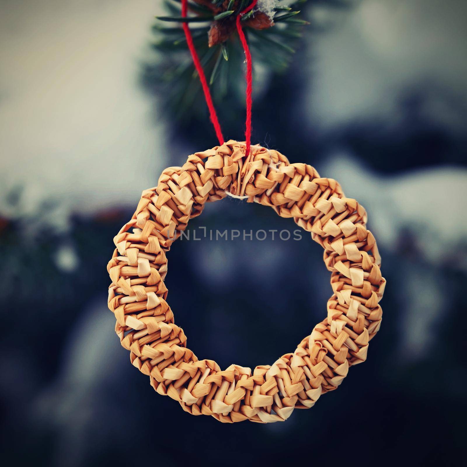 Beautiful natural Christmas decorations made of straw on a snowy Christmas tree. Winter nature colorful outdoor background for the holidays.