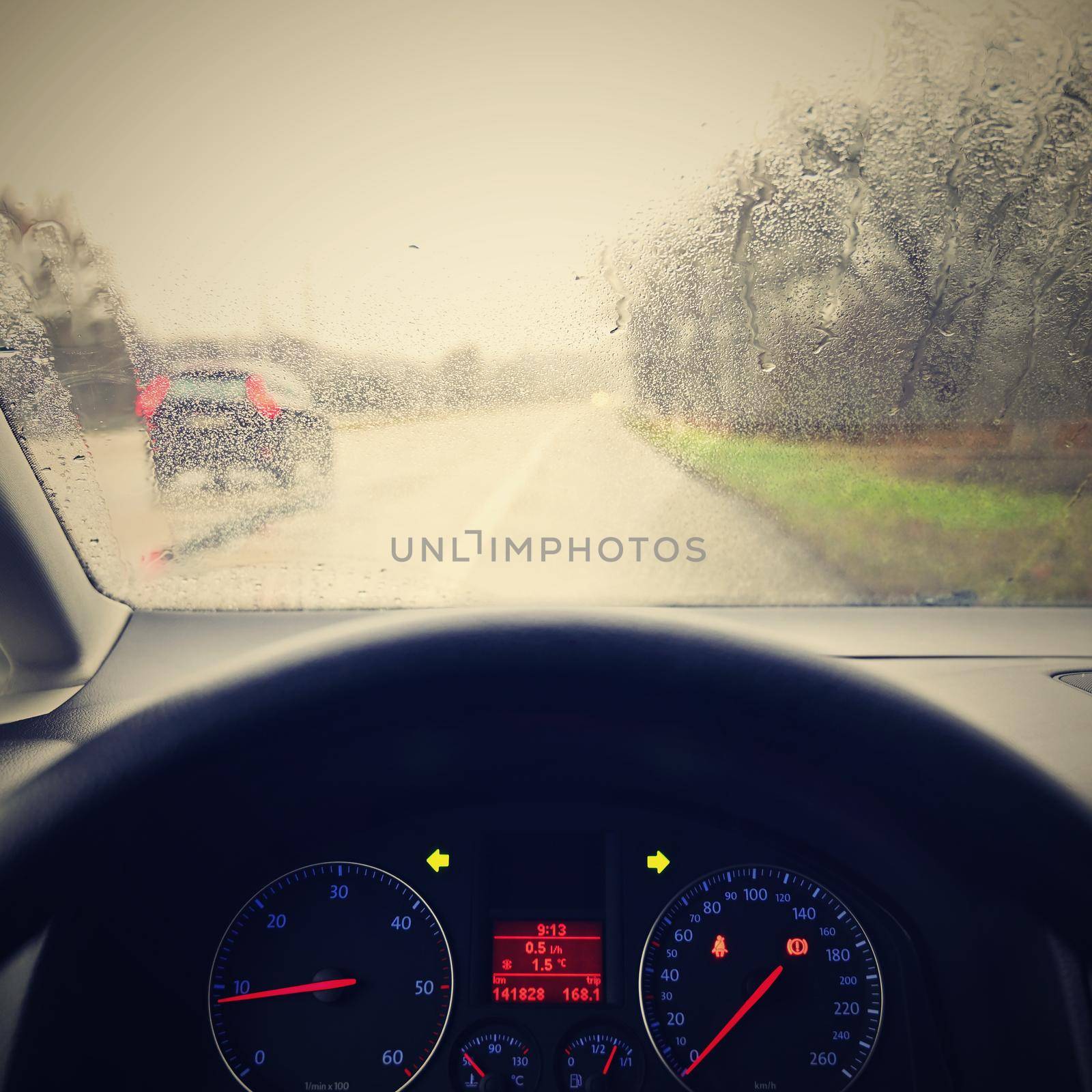 View from the driver - car interior with steering wheel and dashboard. Winter bad rainy weather and dangerous driving on the road. by Montypeter