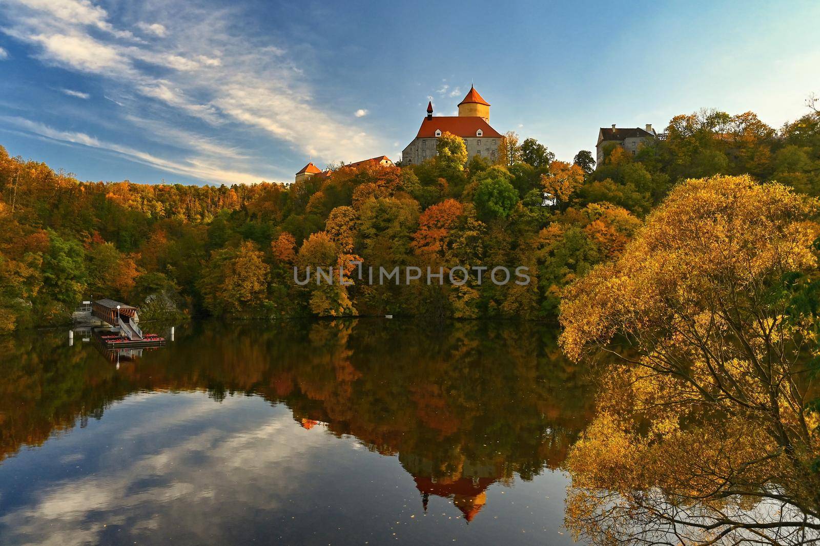 Beautiful autumn landscape with old castle Veveri at sunset and beautiful blue sky with clouds. Colorful nature background on autumn season. Brno - Czech Republic.