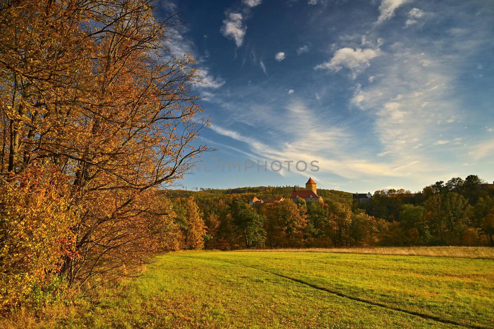 Beautiful autumn landscape with old castle Veveri at sunset and beautiful blue sky with clouds. Colorful nature background on autumn season. Brno - Czech Republic.
