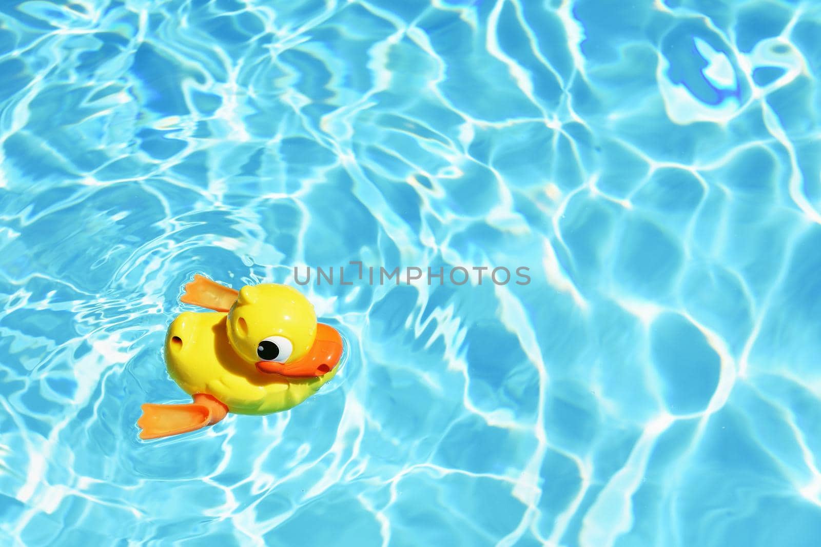 Yellow rubber duck on the water in hot sunny day. Summer background for traveling and vacation. Holiday idyllic.