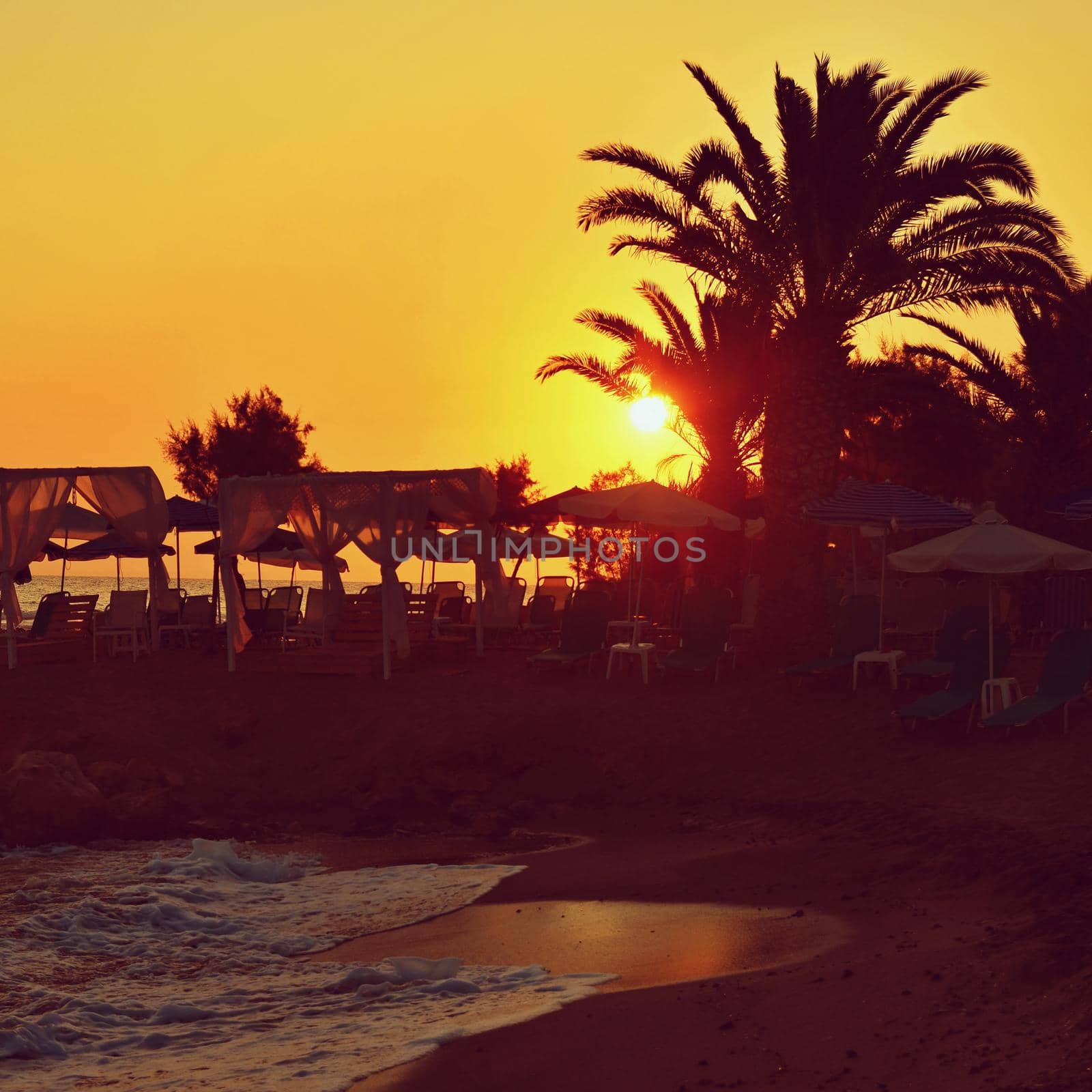 Beautiful summer sunset by the sea. Amazing scenery on the beach with waves and reflection of the sun. Background for holiday and vacation travel. Greece Crete Island.