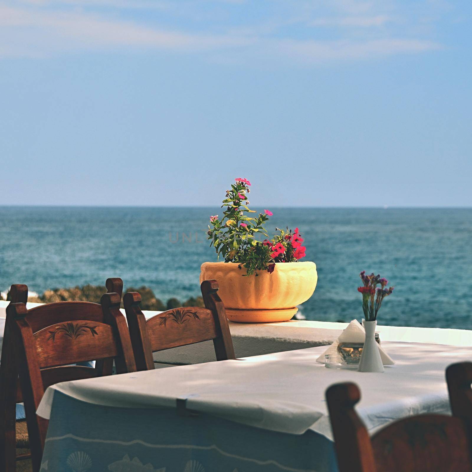 A covered table in a Greek tavern and a sea. Summer background for travel and holidays.
