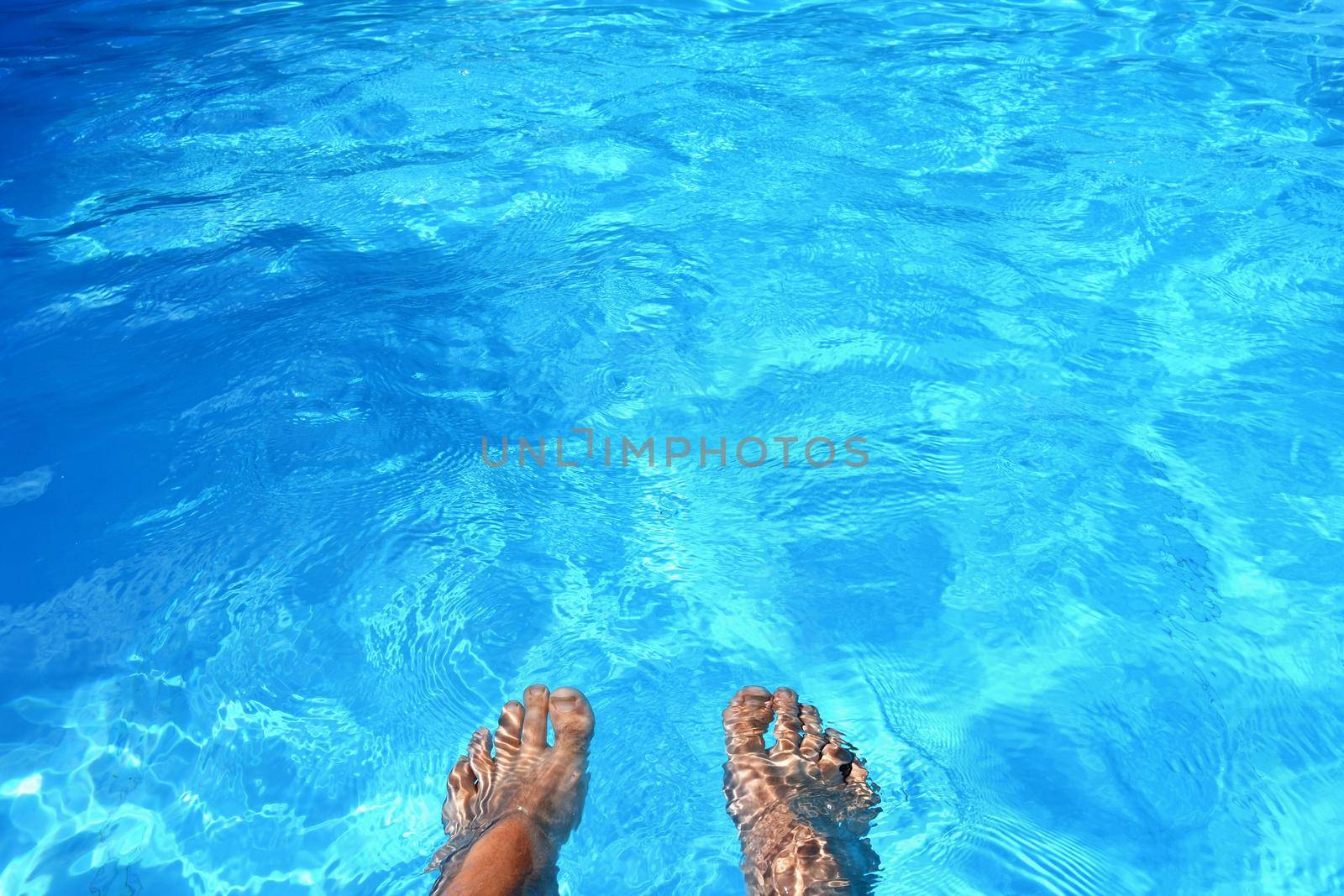 Legs in the pool with clean water. Summer background for traveling.