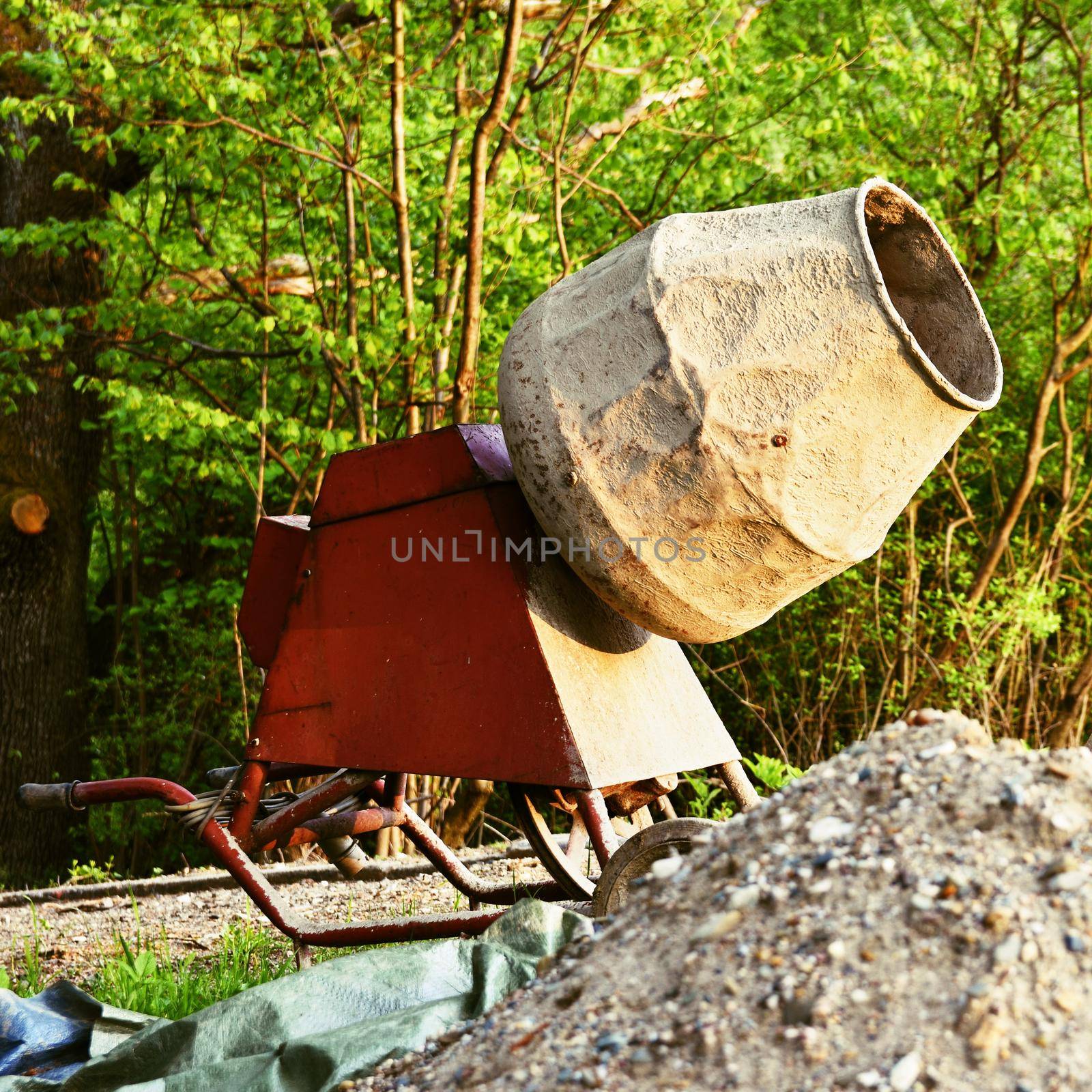 Concrete mixer at sunset. Natural green background.