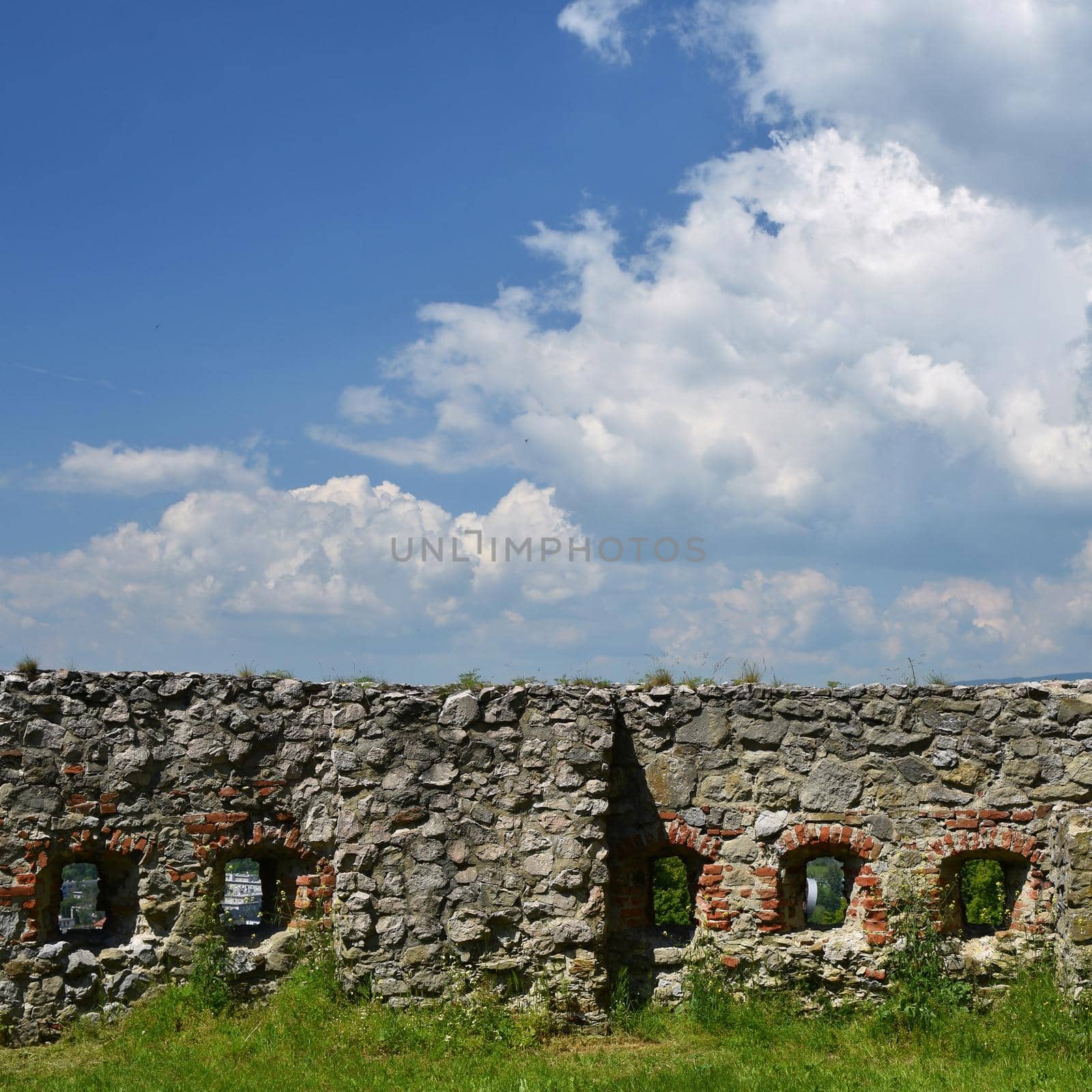 The walls of the castle with a background of blue sky and clouds. by Montypeter