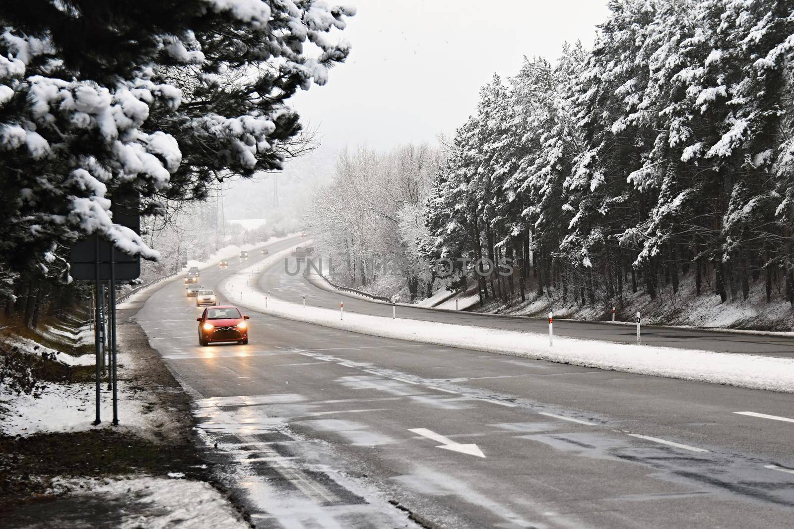 Cars on winter road with snow. Dangerous automobile traffic in bad weather.