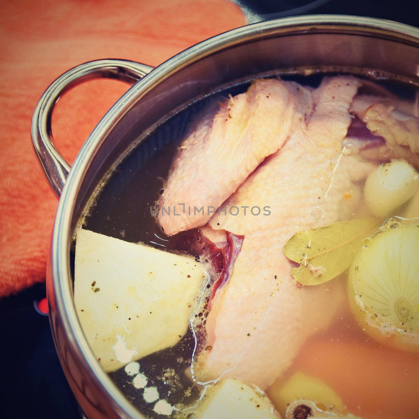 Preparing homemade chicken soup - broth. Pot on the stove in the kitchen with ingredients for cooking. by Montypeter