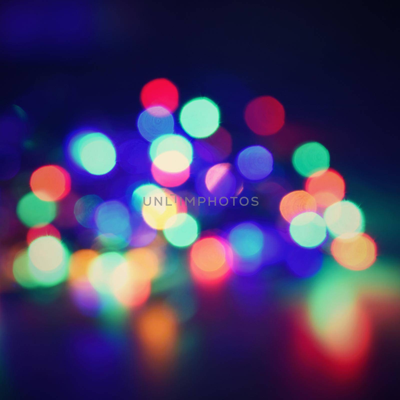 Christmas blurred lights on black background with copy space. Abstract colorful reflections of bulbs on a Christmas tree.