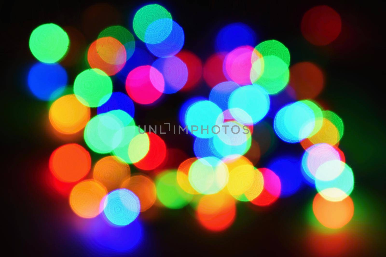 Christmas lights on black background with copy space. Colored reflecting surface.