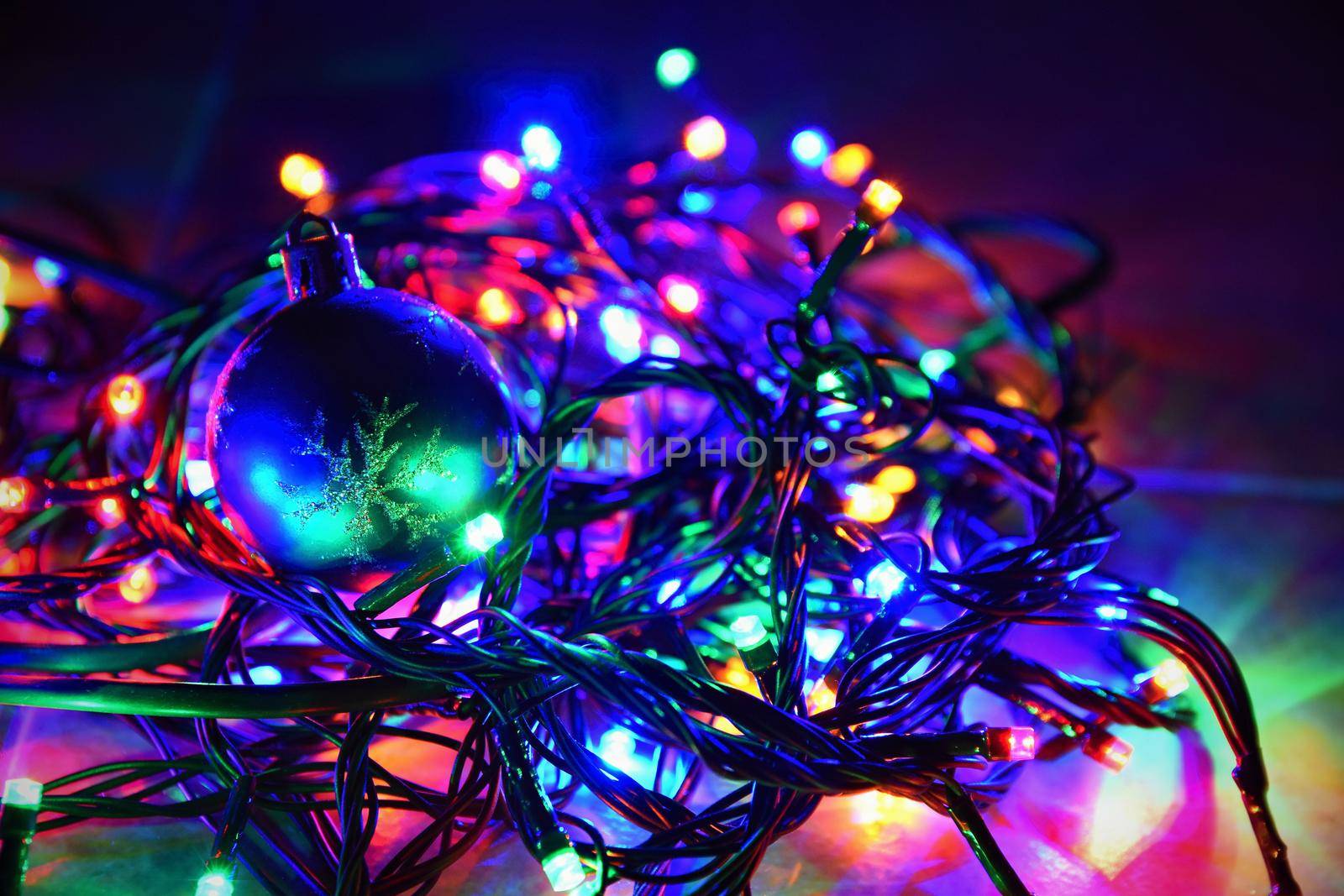 Christmas lights on black background with copy space. Colored reflecting surface.