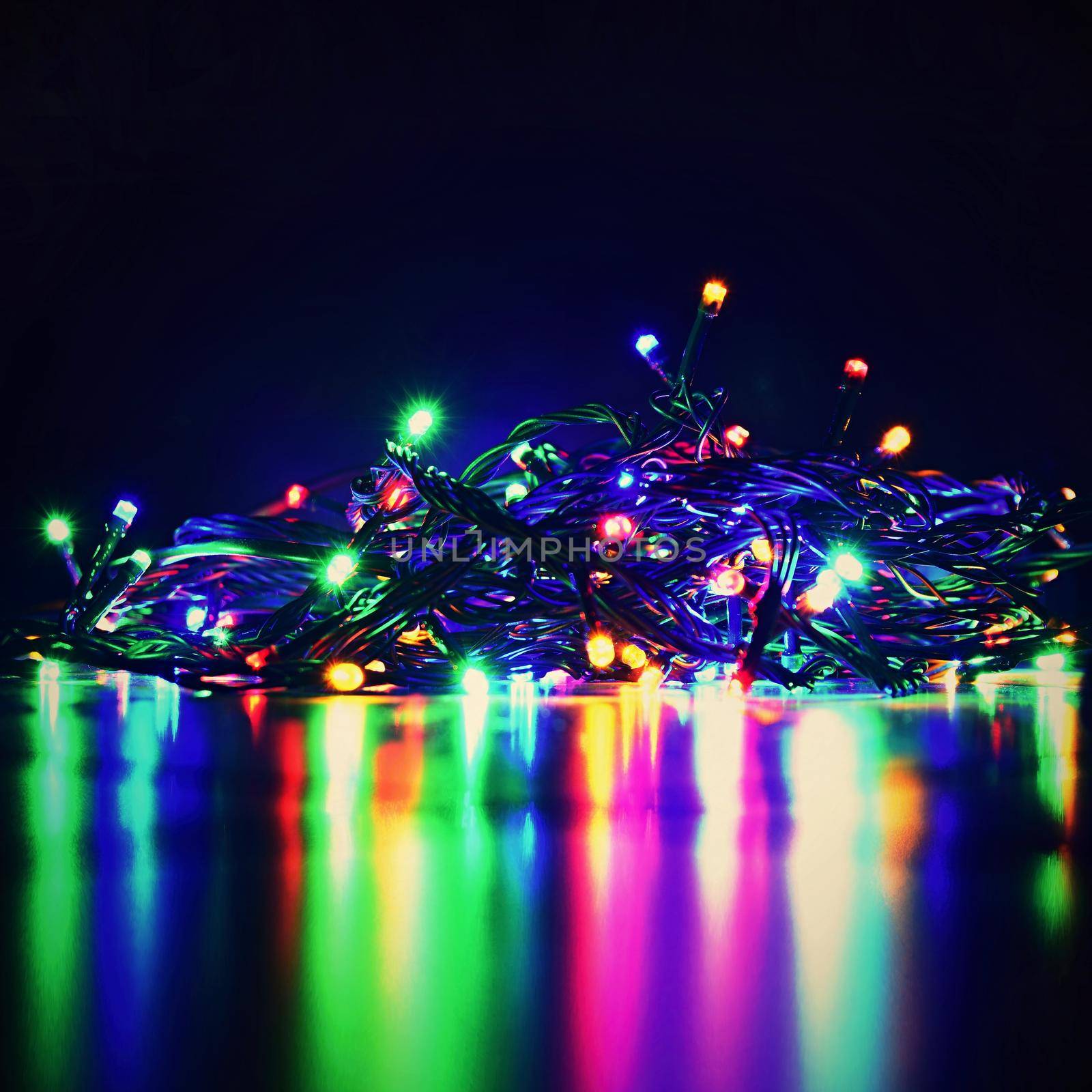 Christmas lights on black background with copy space. Colored reflecting surface. by Montypeter