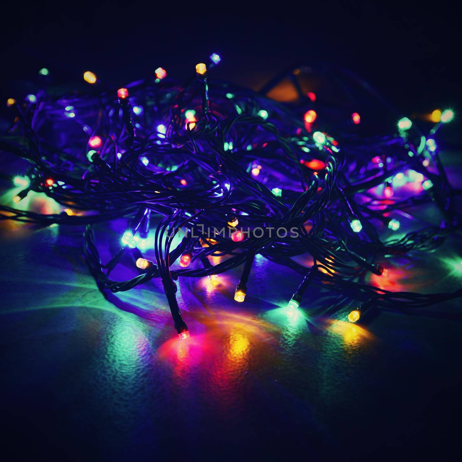 Christmas lights on black background with copy space. Colored reflecting surface. by Montypeter