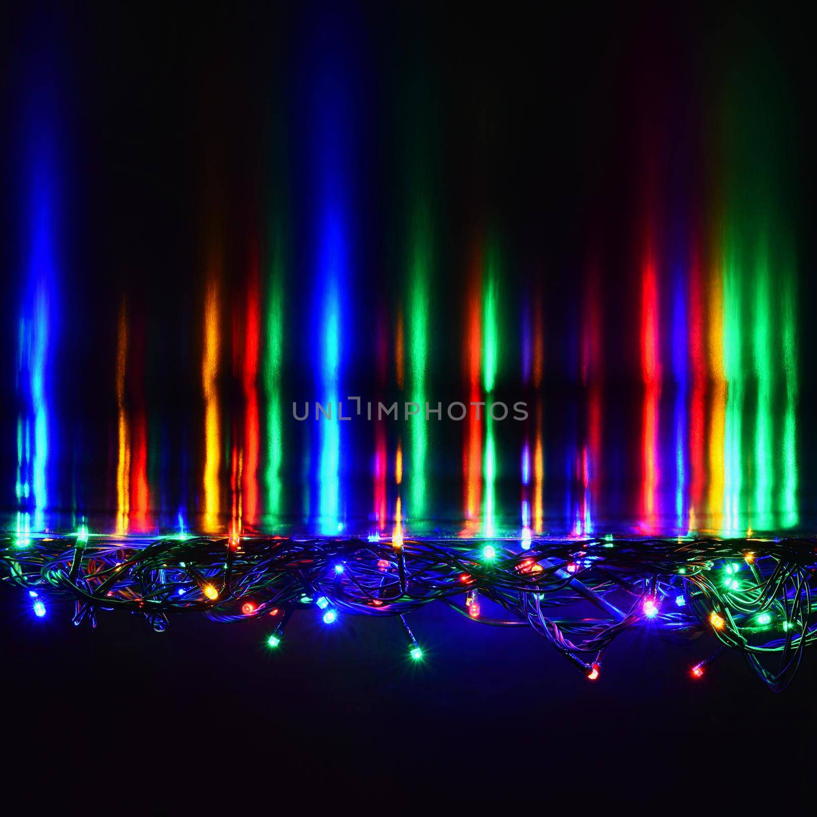 Christmas lights on black background with copy space. Colored reflecting surface. by Montypeter