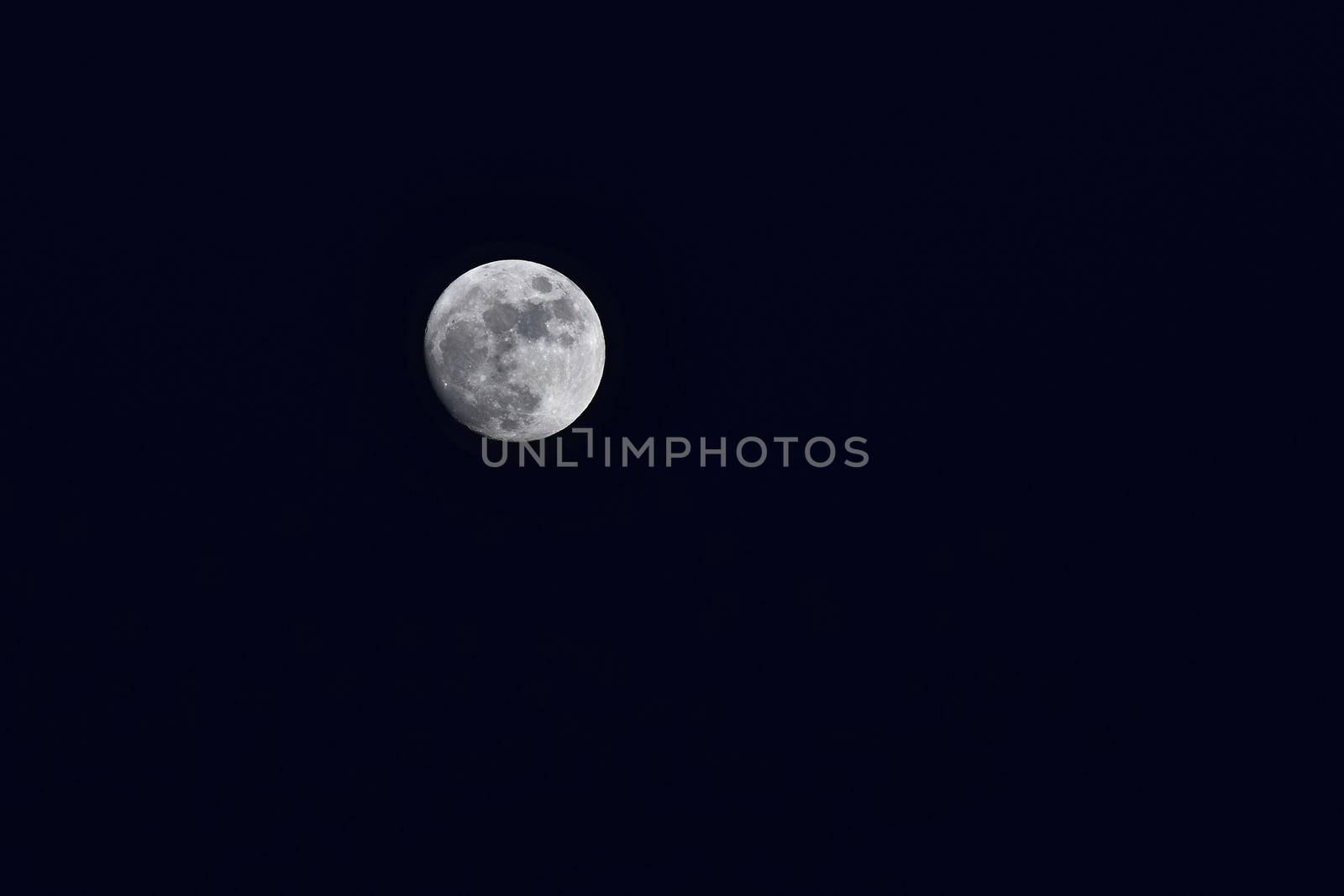 Full moon over dark black sky at night by Montypeter