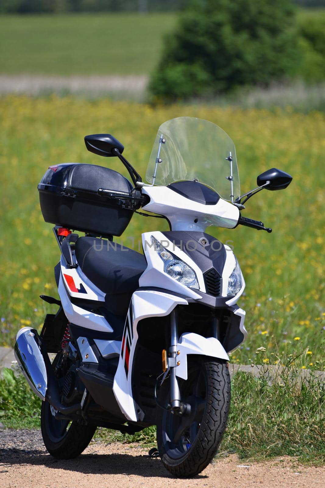 Beautiful white little scooter in nature. Blurred colorful background.
The ideal means of transport into the city and into the countryside. Transport.