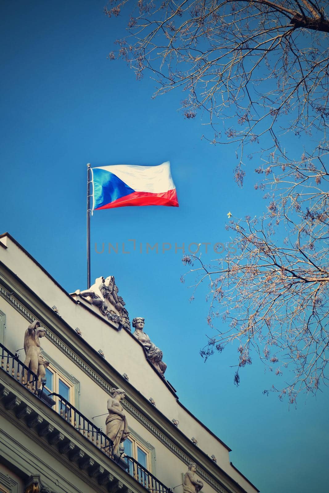 The flag of the Czech Republic on a building with blue sky and the sun in the background. by Montypeter