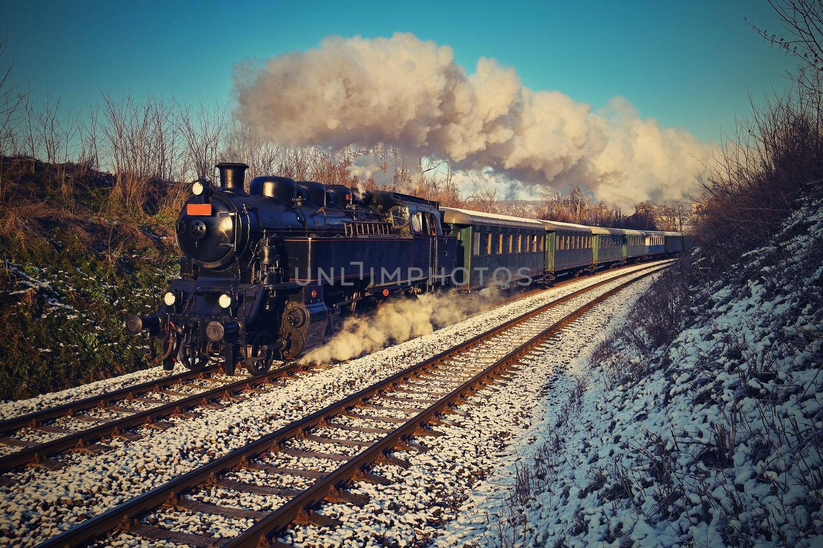 Beautiful old steam train with wagons running on rails at sunset. Excursions for children and parents on festive special days. Czech Republic Europe.