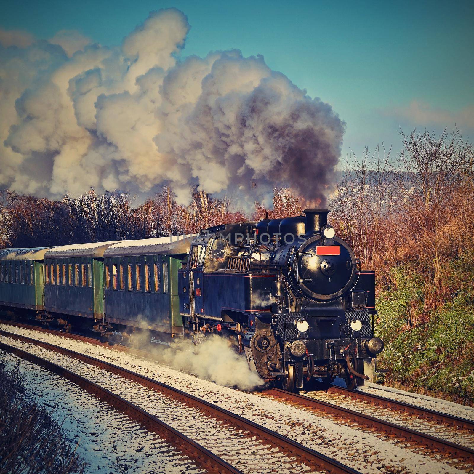 Beautiful old steam train with wagons running on rails at sunset. Excursions for children and parents on festive special days. Czech Republic Europe. by Montypeter