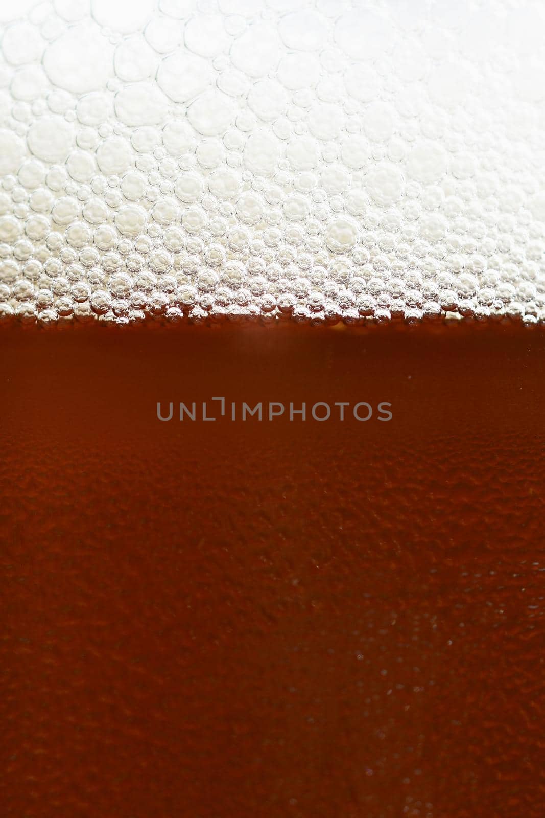 Beer. Beautiful detail of beaten glass of beer with foam. Abstract colorful background.