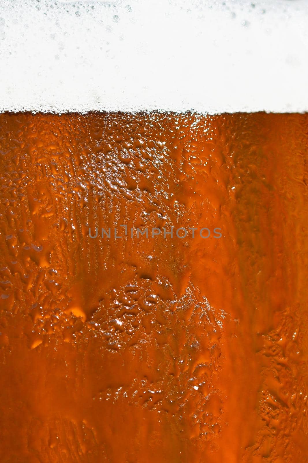 Beer. Beautiful detail of beaten glass of beer with foam. Abstract colorful background. by Montypeter