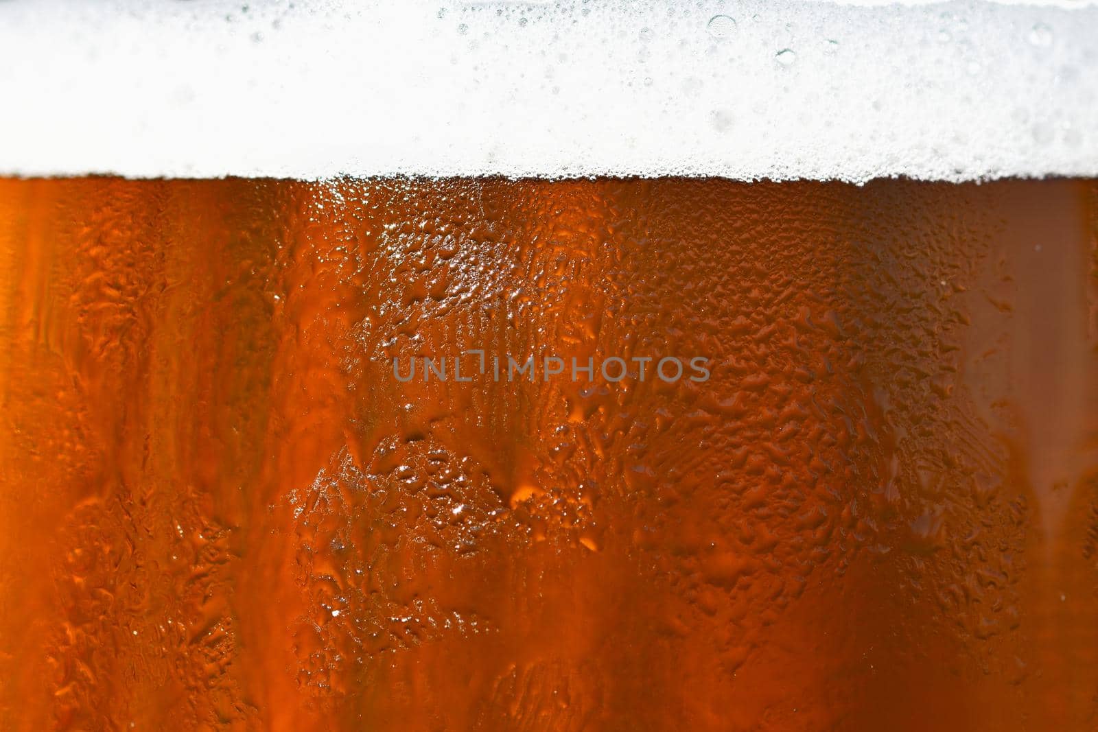 Beer. Beautiful detail of beaten glass of beer with foam. Abstract colorful background.