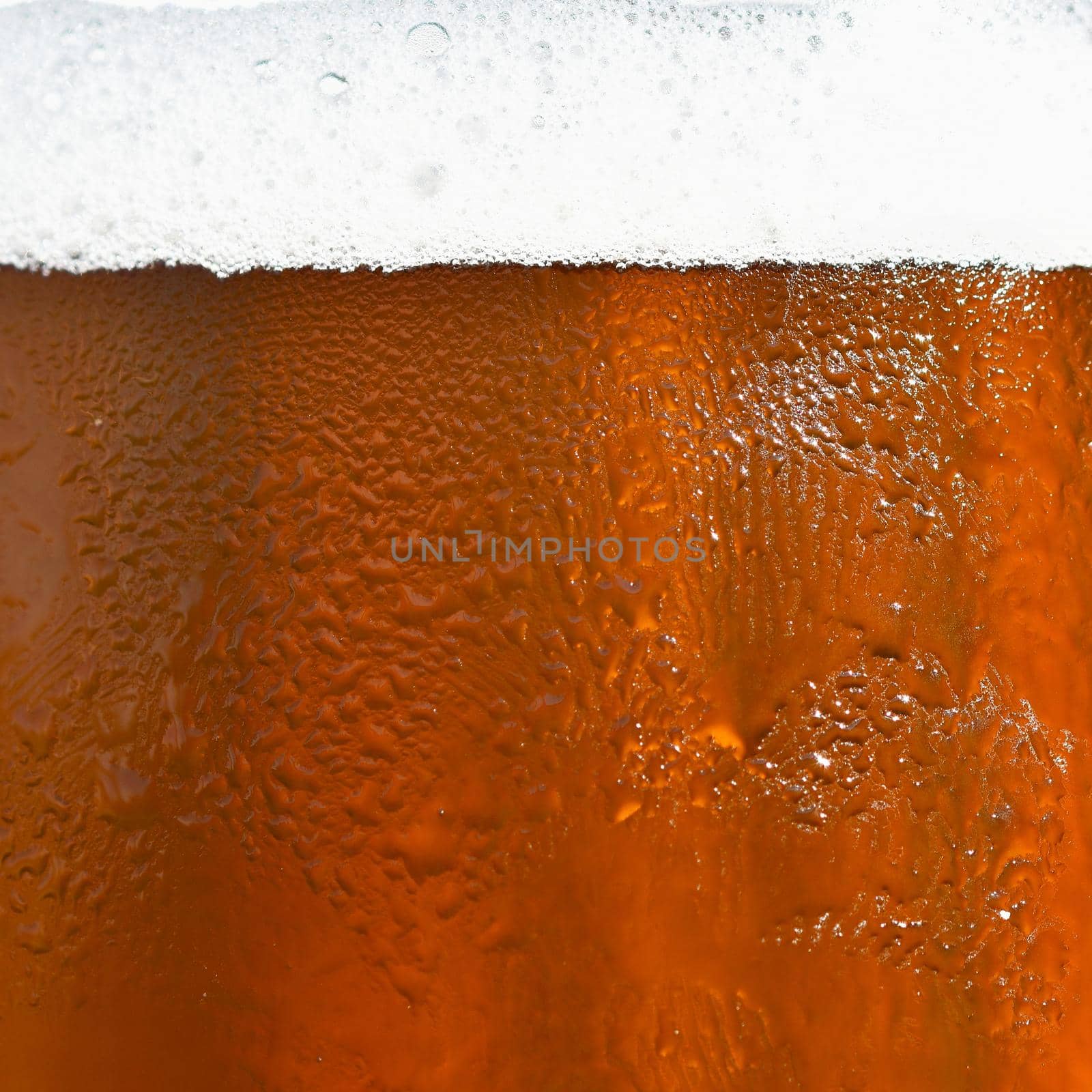 Beer. Beautiful detail of beaten glass of beer with foam. Abstract colorful background. by Montypeter