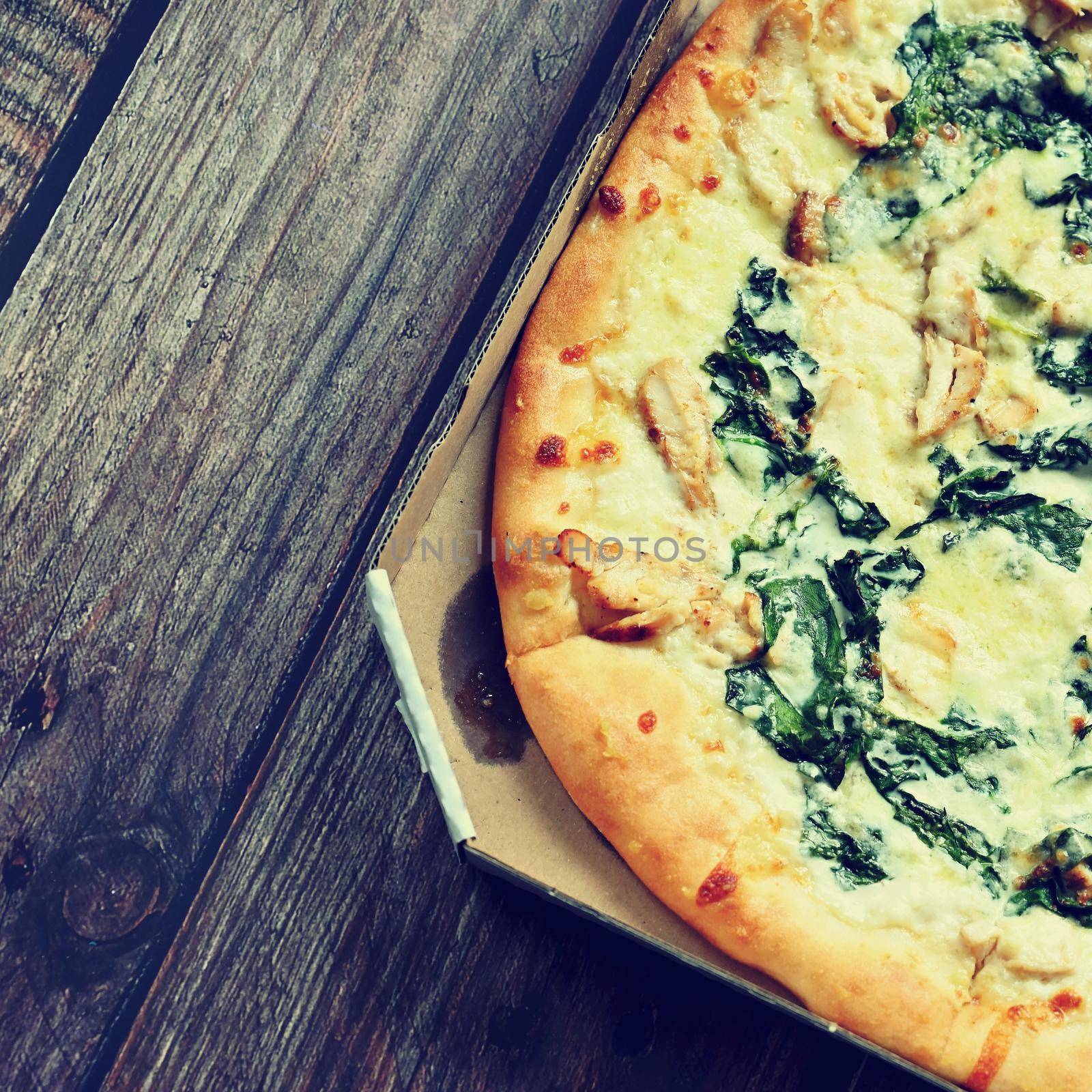 Delicious fresh pizza served on wooden table. Pizza with cream and spinach ready for delivery in a box. by Montypeter