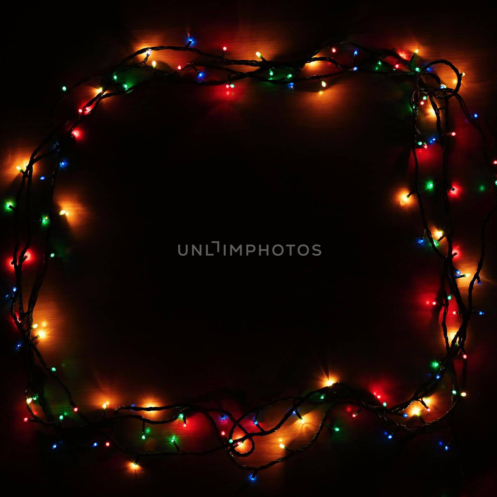 Christmas lights on black background with copy space. Colored reflecting surface. by Montypeter