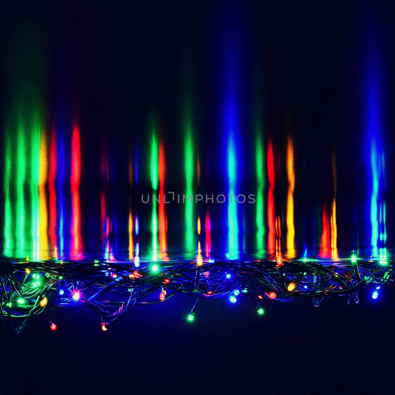 Christmas lights on black background with copy space. Colored reflecting surface.