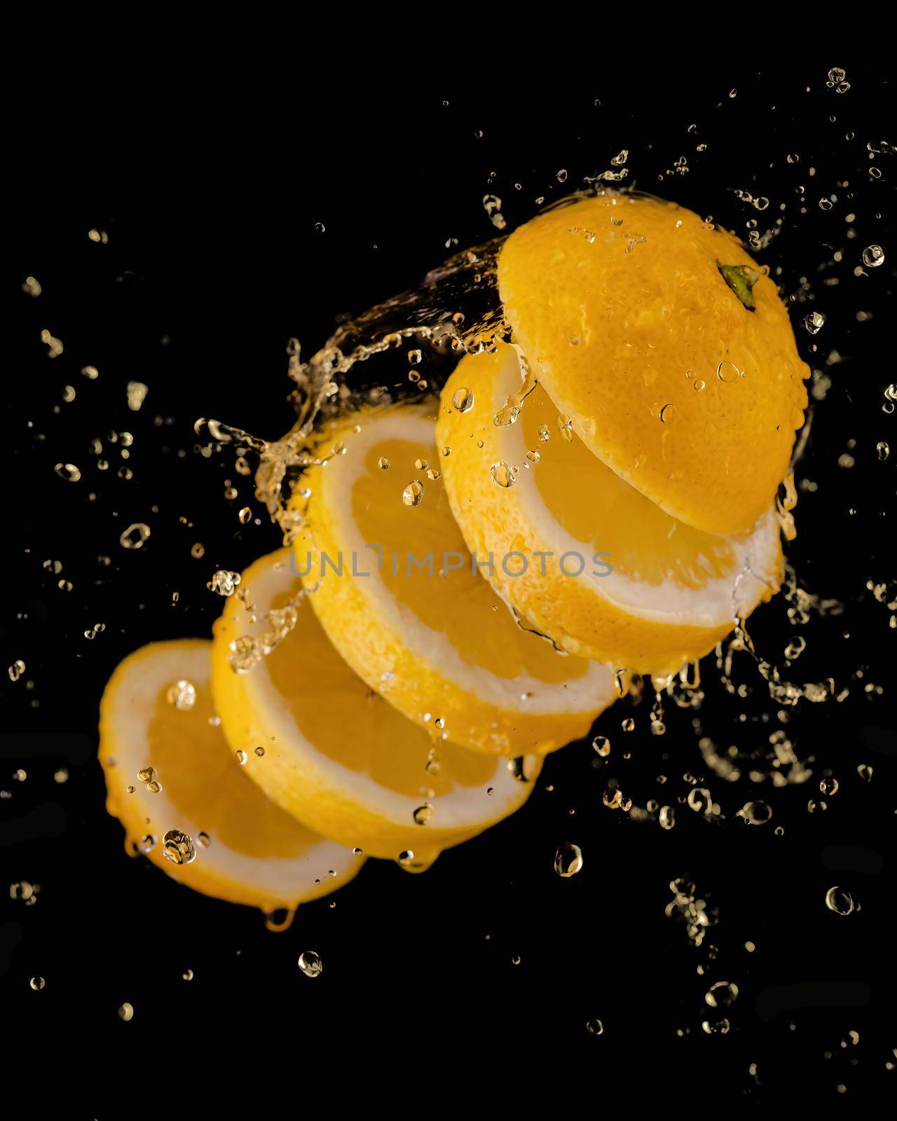 Juice or liquid splashing with yellow lemon isolated on black background.