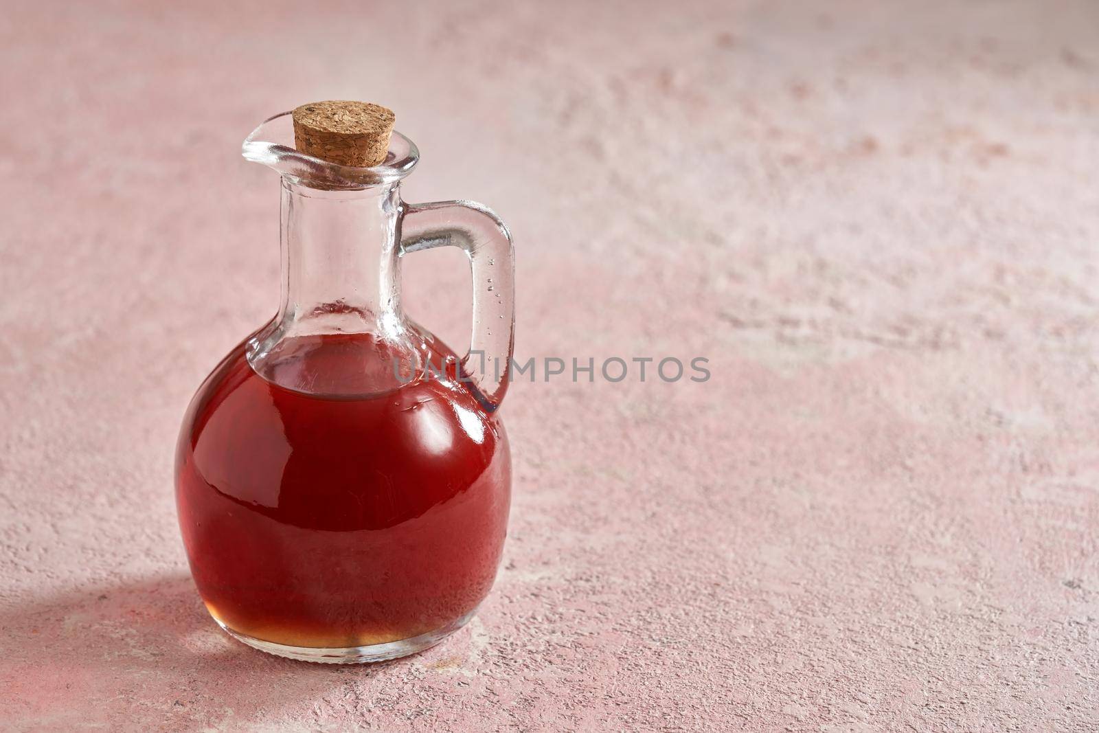 A bottle of rose hip seed on pink pastel background with copy space