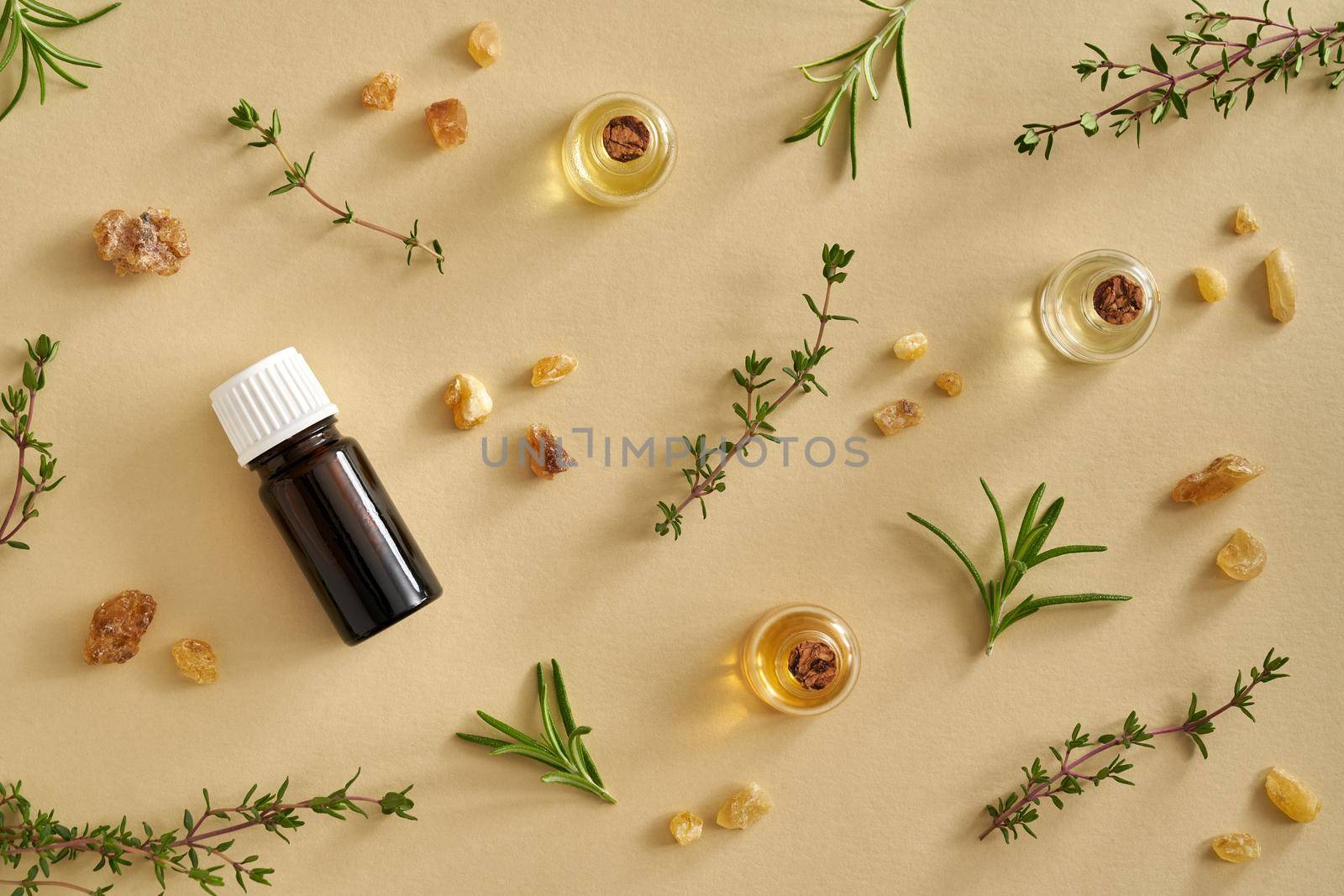 Pastel yellow background or flat lay with bottles of essential oil, frankincense and fresh herbs