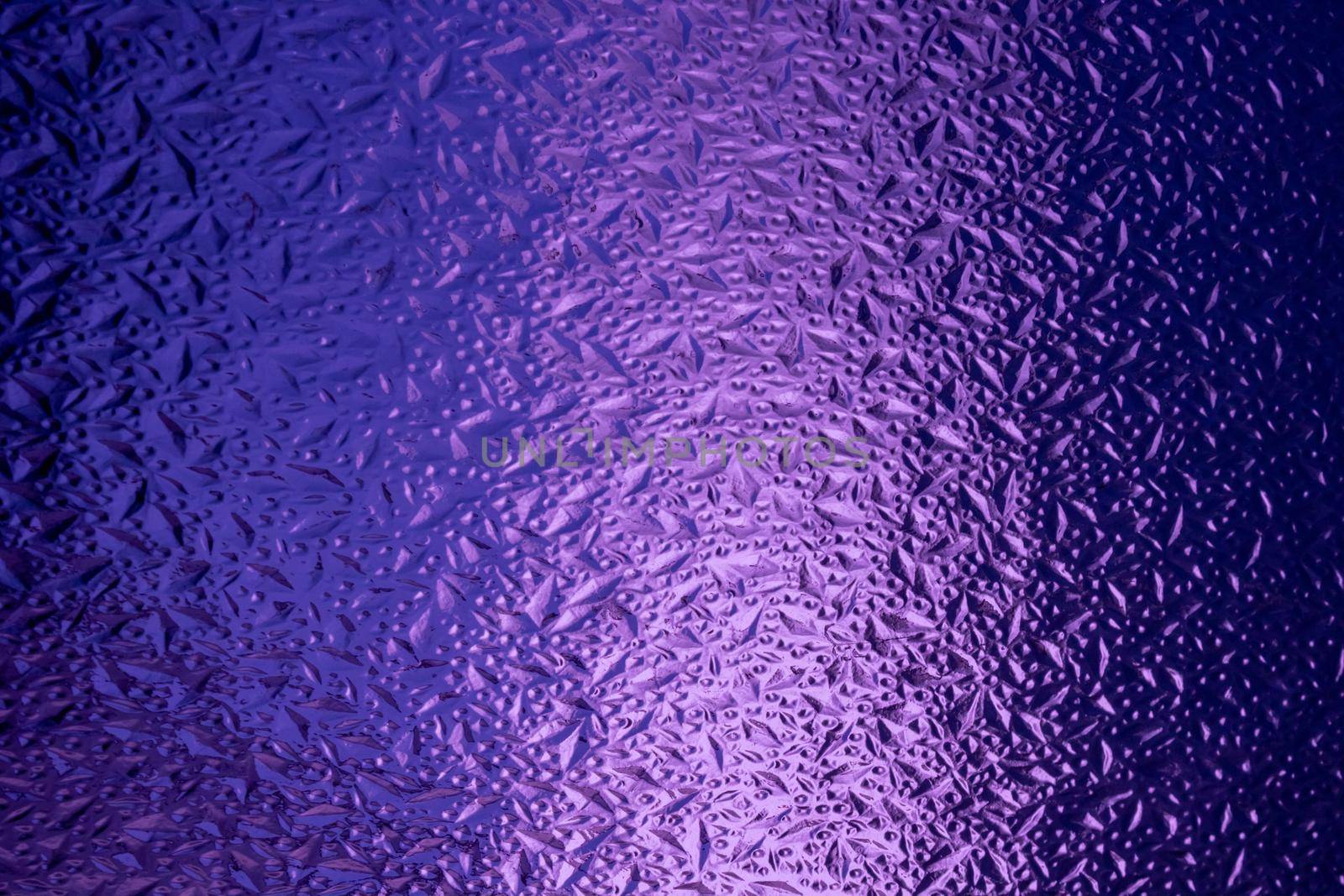 Abstract background made of corrugated purple glass.Glass background.