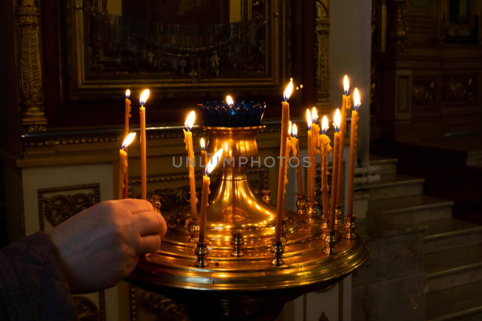 A woman's hand lights candles in a church.The concept of Easter and Christmas.