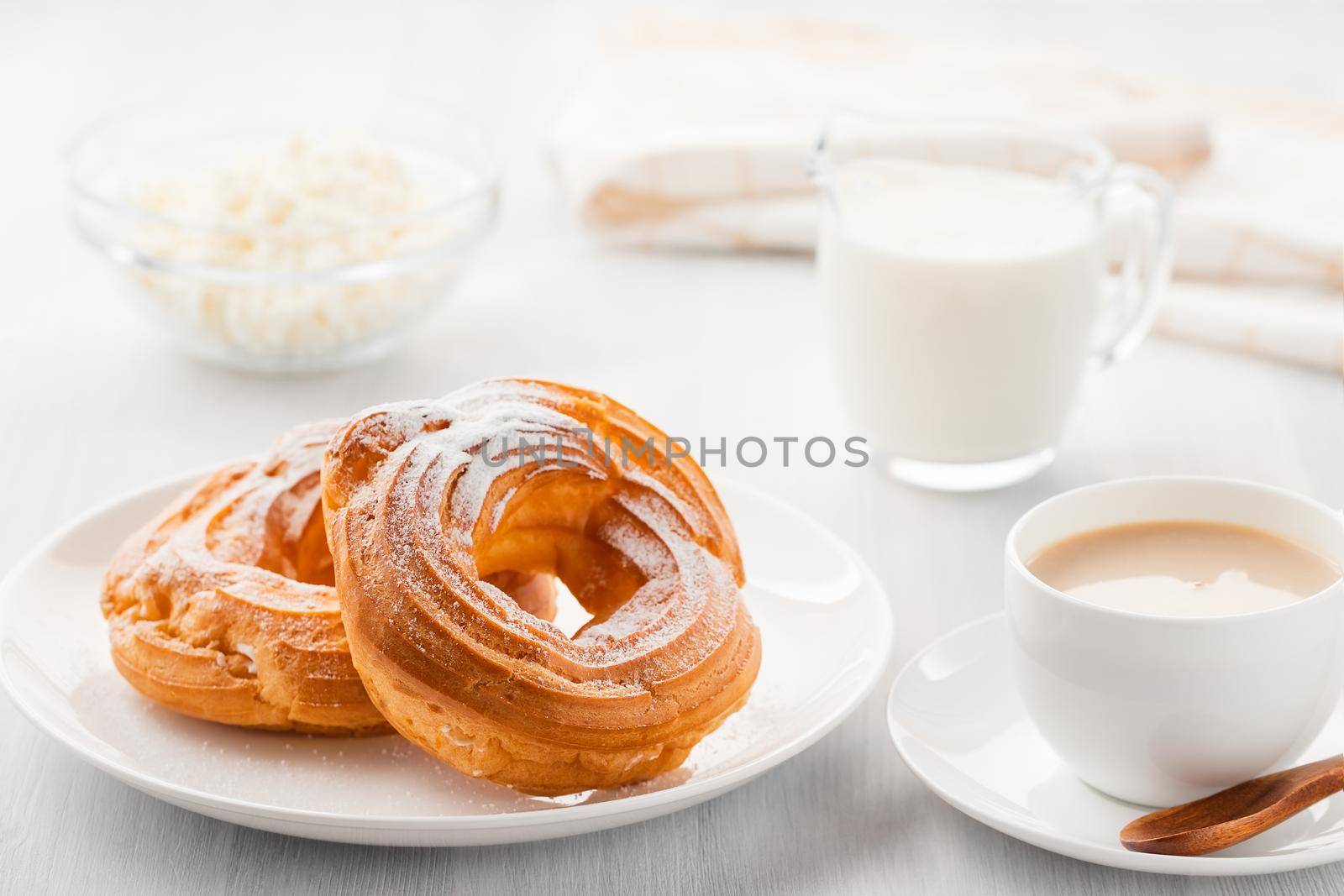 Morning coffee with cake. Custard rings, coffee, cream, cottage cheese on a white wooden table by galsand