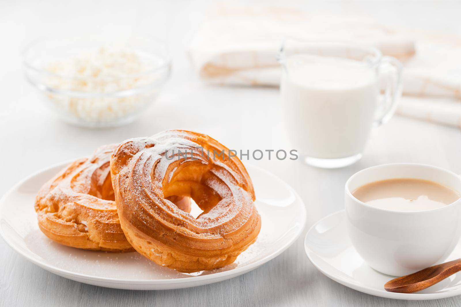 Morning coffee with cake. Custard rings, coffee, cream, cottage cheese on a white wooden table.