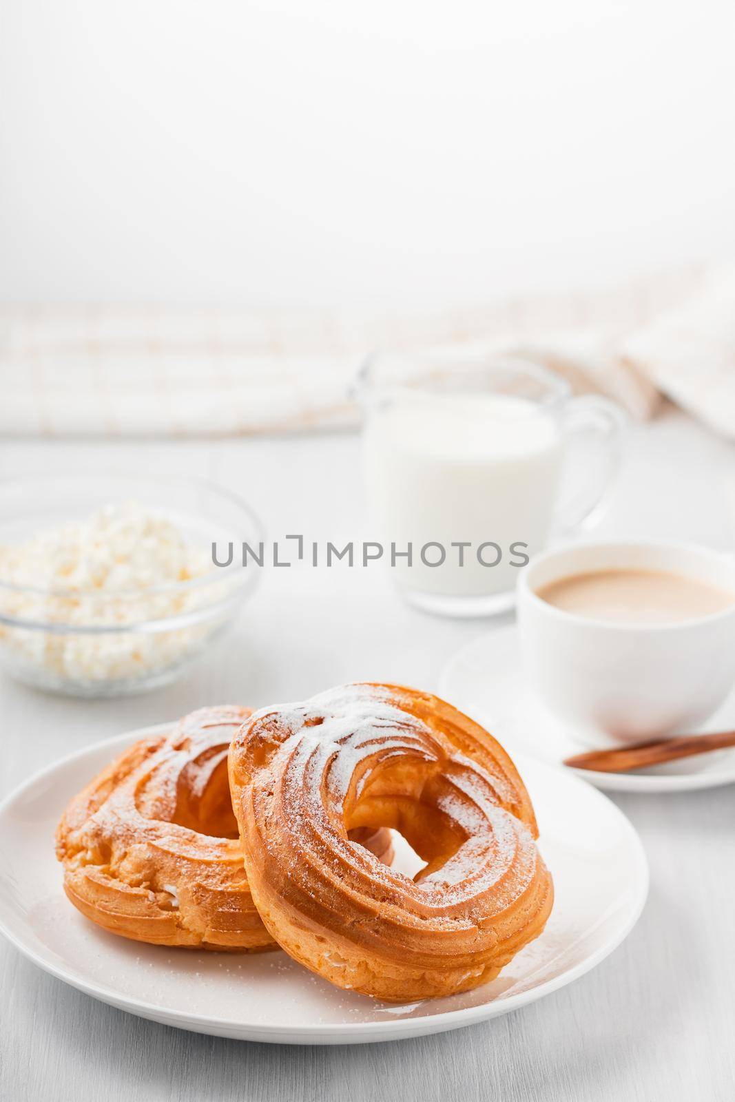 Morning coffee with cake. Custard rings, coffee, cream, cottage cheese on a white wooden table. Vertical image.