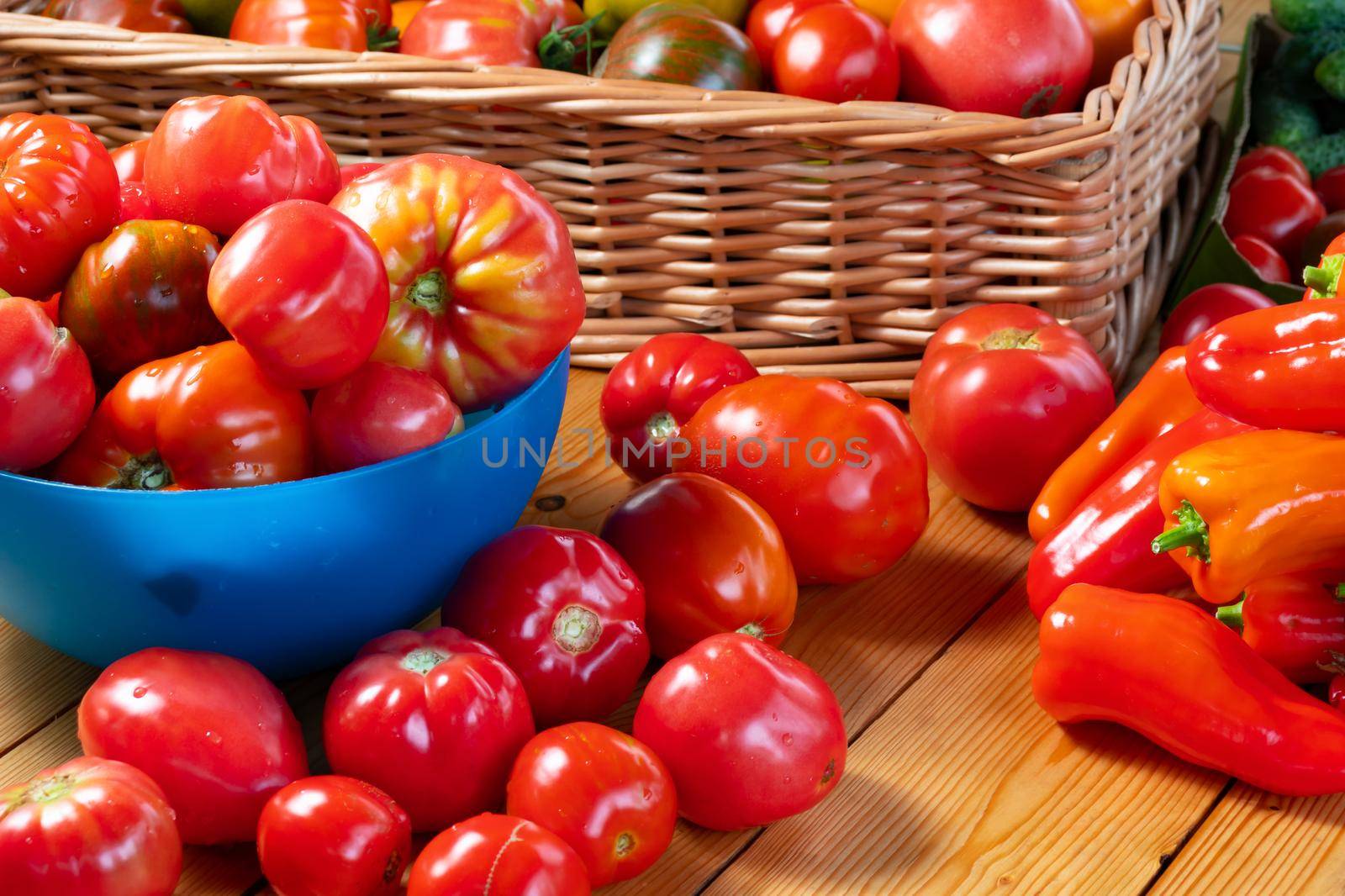 Fresh ripe natural tomatoes and peppers on a wooden table and in a bowl - farm harvest.