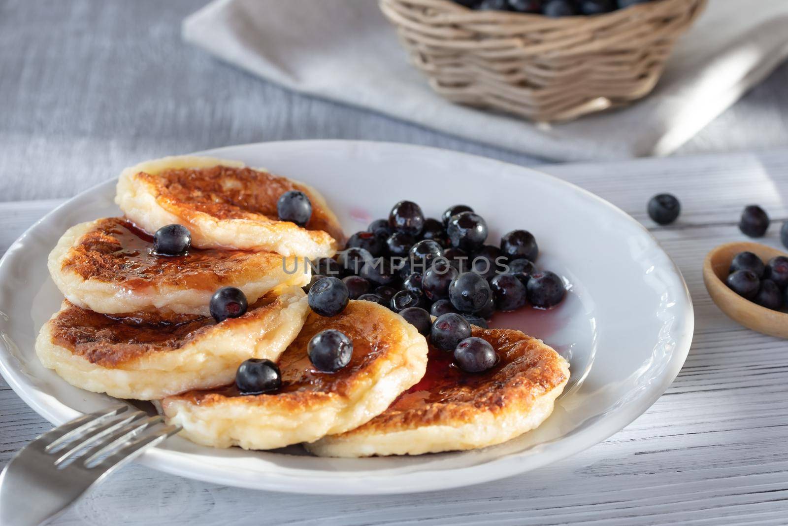 Fresh cottage pancakes with cheese and blueberries in syrup. Summer breakfast in the village.